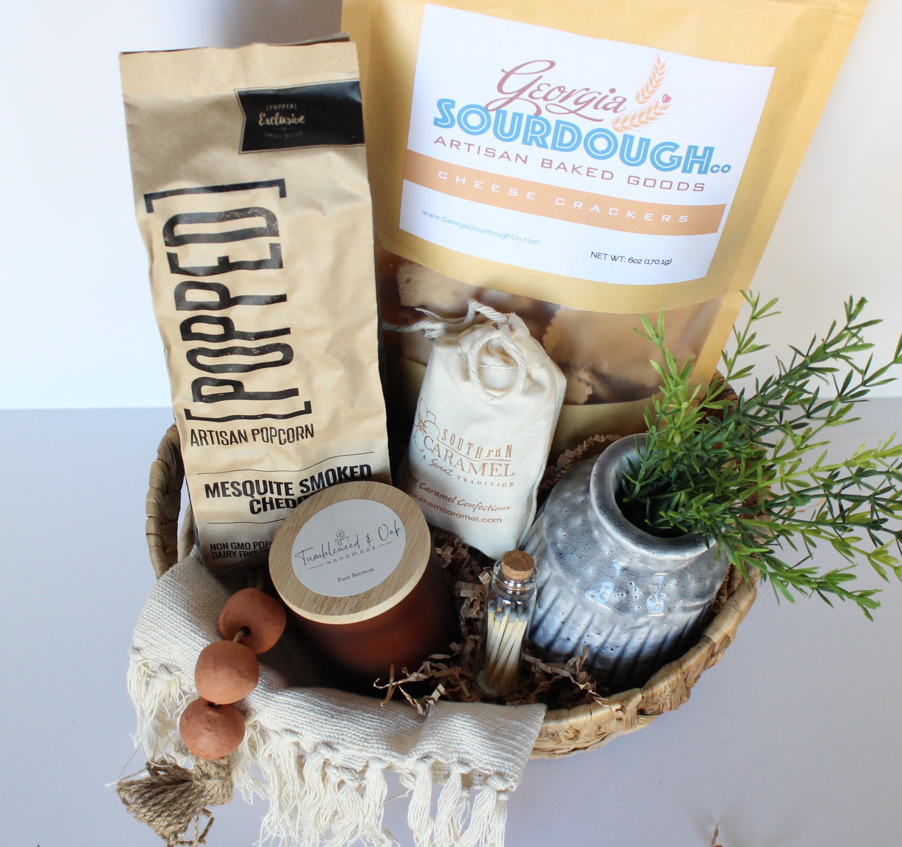 Gift basket with Georgia Sourdough bread, popcorn, candles, and a vase on a white background