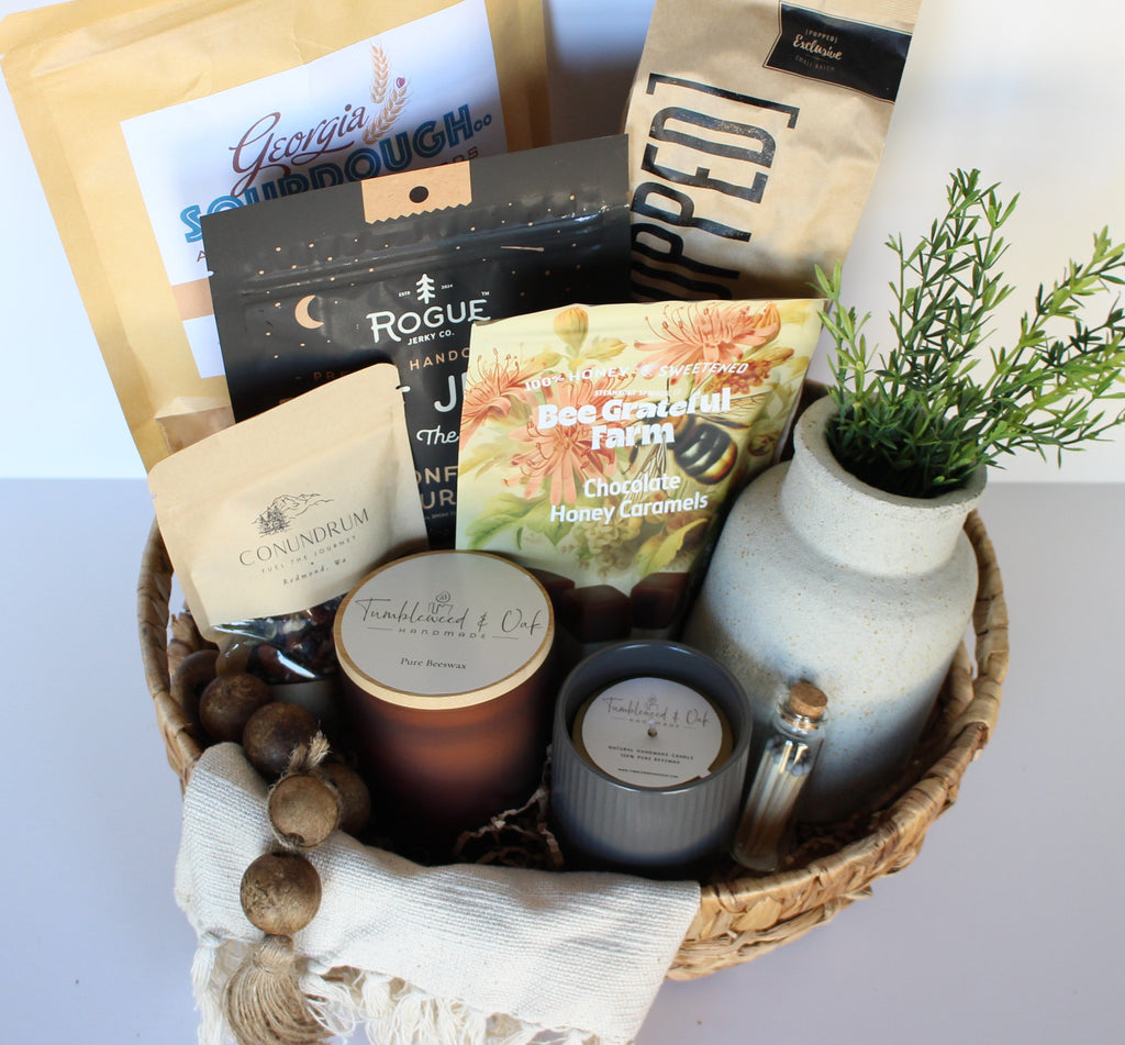 Gift basket with candles, snacks, and a plant on a light background